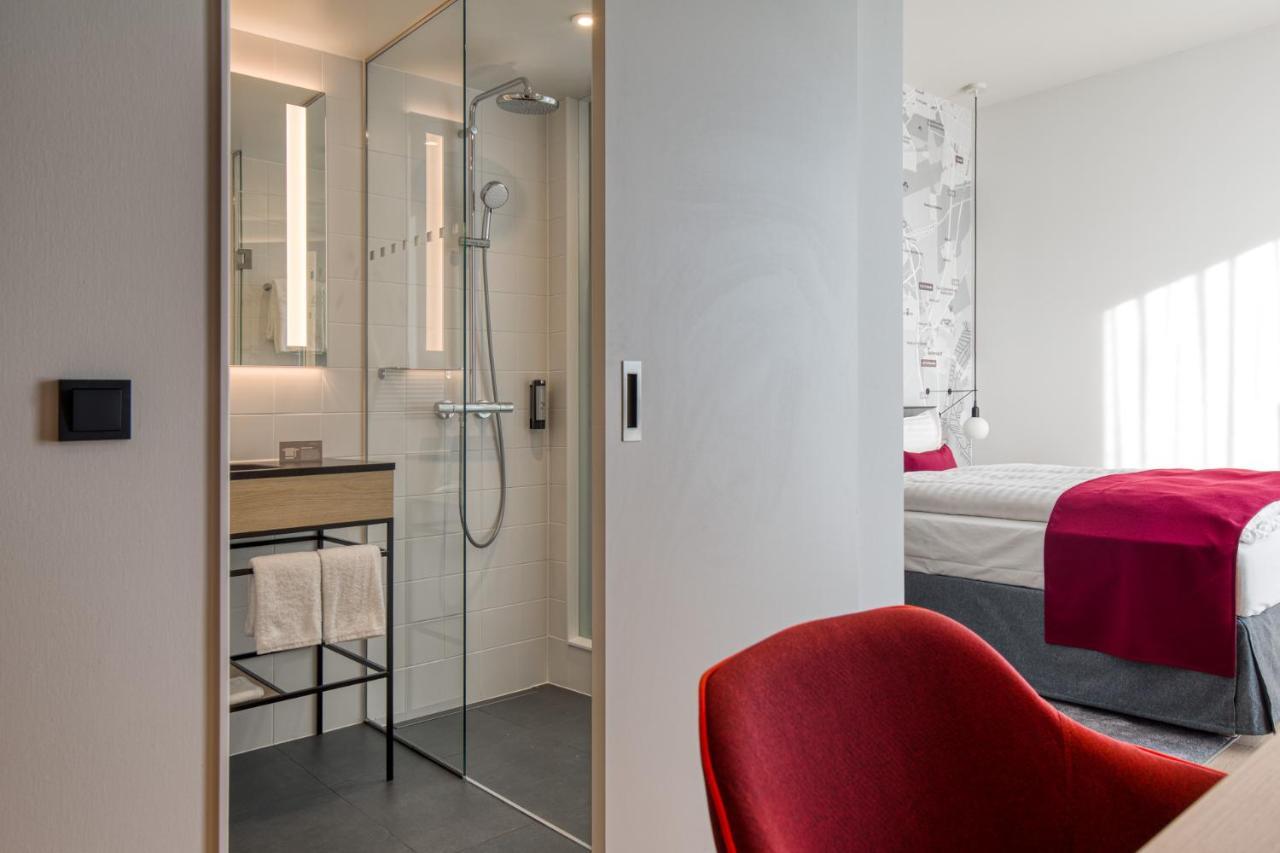 Intercityhotel Berlin Airport Ber Terminal 1 & 2 Schönefeld Exteriör bild The photo shows a modern hotel room or bathroom space. On the left, there is a glass-enclosed shower area with a sleek design, featuring a showerhead and minimalist fixtures. Adjacent to the shower, there's a sink area with a stylish countertop and a